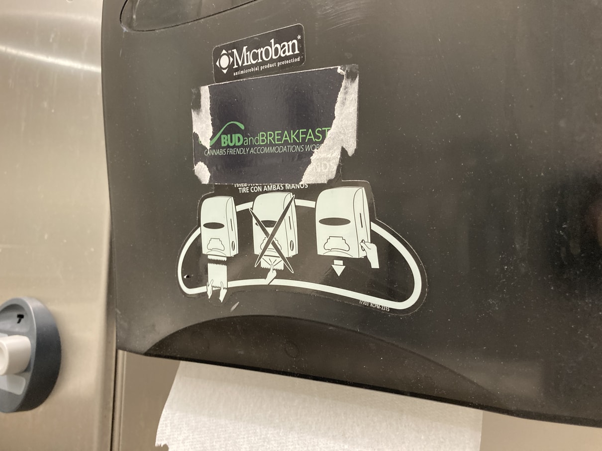 Worn-out sticker on paper towel dispenser advertising for a bud and breakfast site.