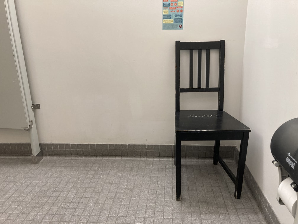 Black wooden chair in corner of stall.